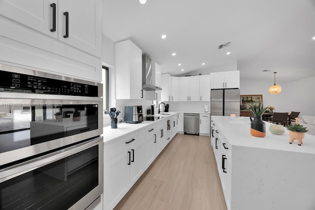 kitchen with light countertops, white cabinetry, visible vents, wall chimney exhaust hood, and appliances with stainless steel finishes