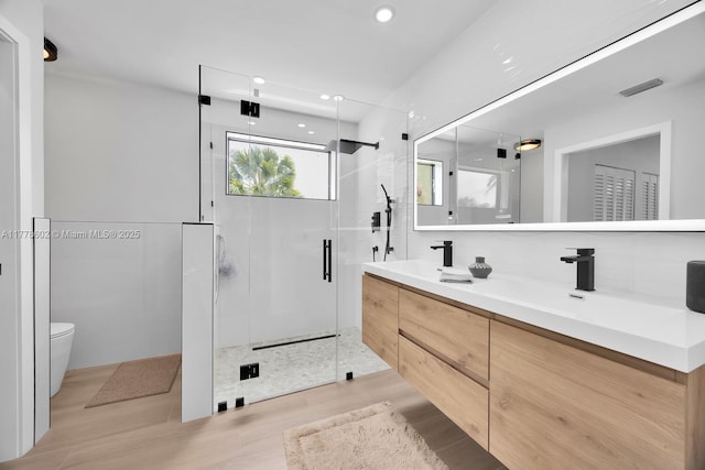 full bathroom featuring double vanity, a stall shower, toilet, visible vents, and a sink