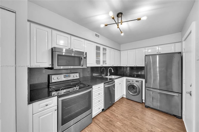 6770 Indian Creek Dr Unit 9G, Miami Beach, FL 33141 - kitchen featuring stainless steel appliances, washer / dryer, a chandelier, dark countertops, and white cabinets