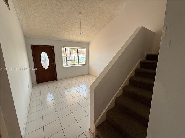 foyer with a textured ceiling, light tile patterned floors, baseboards, and stairs