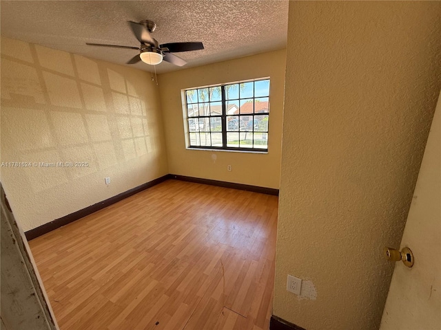 unfurnished room featuring a textured ceiling, ceiling fan, and a textured wall