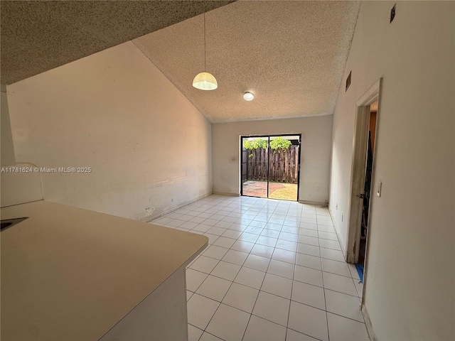 spare room featuring a textured ceiling, visible vents, vaulted ceiling, and light tile patterned flooring