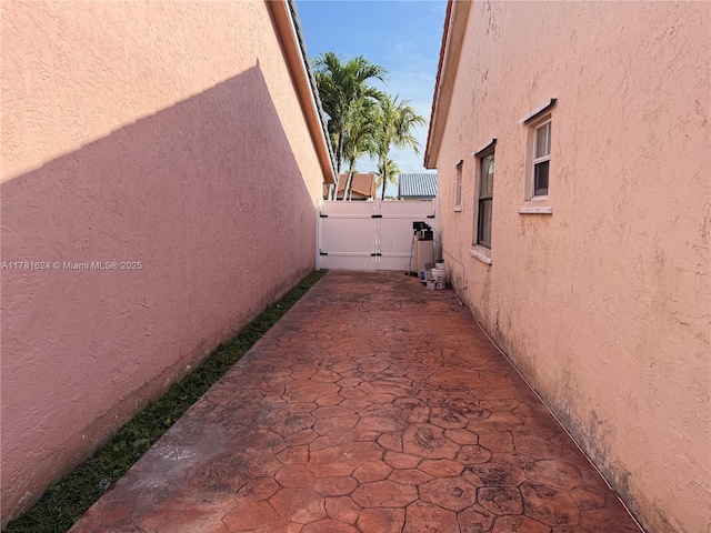 view of side of home with a gate, stucco siding, and a patio area