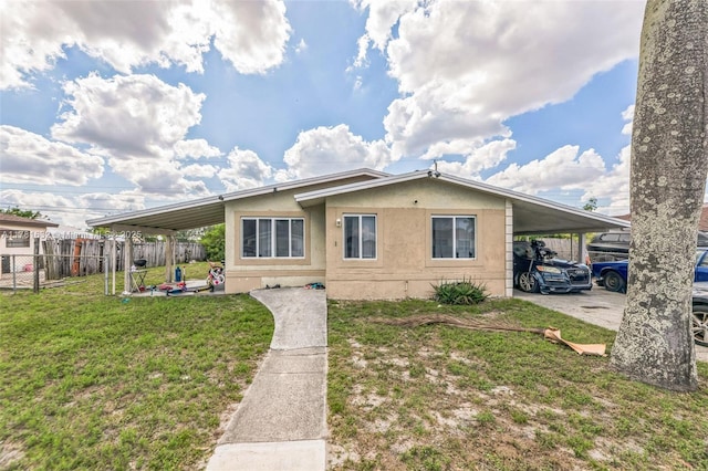 view of front of property with an attached carport, stucco siding, fence, and a front lawn