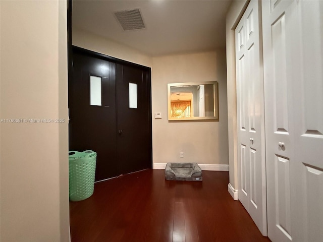 foyer entrance with visible vents, dark wood-style flooring, and baseboards