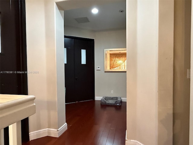 hall with dark wood-style flooring, visible vents, baseboards, and recessed lighting