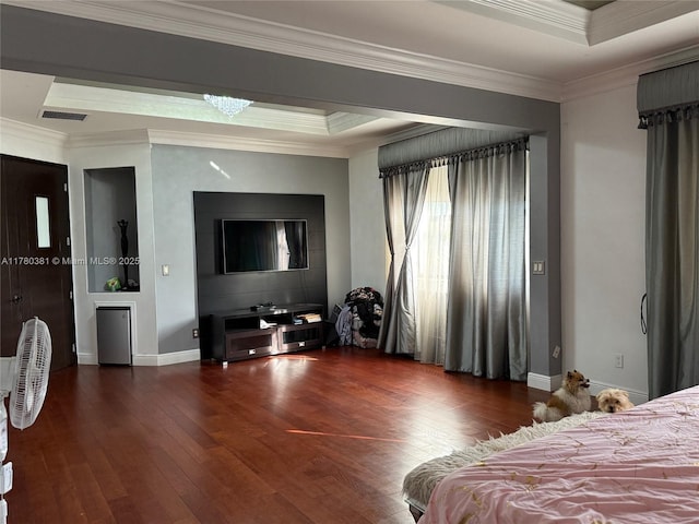 bedroom with baseboards, ornamental molding, visible vents, a tray ceiling, and hardwood / wood-style flooring