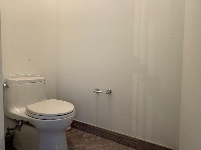 bathroom with toilet, wood finished floors, and baseboards