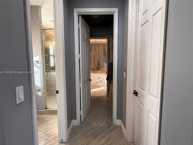 hallway with baseboards and wood finished floors