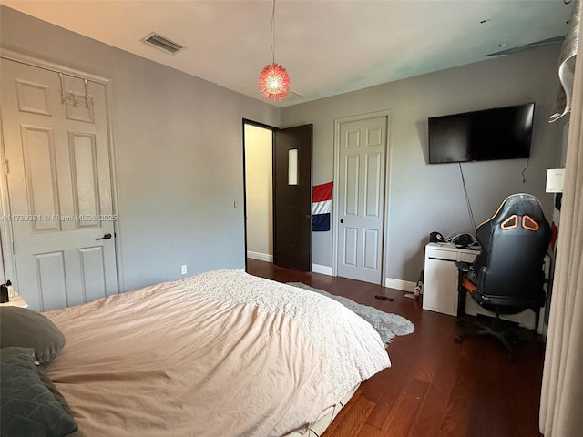 bedroom with visible vents, baseboards, and wood finished floors