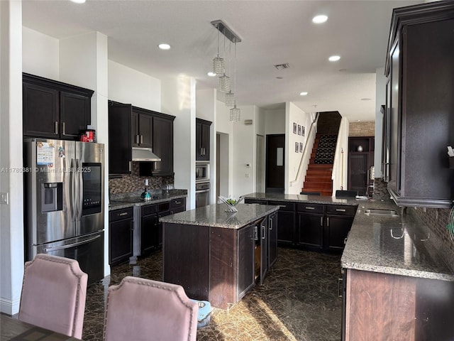 kitchen featuring dark stone countertops, under cabinet range hood, visible vents, appliances with stainless steel finishes, and marble finish floor
