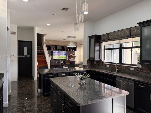 kitchen with tasteful backsplash, a kitchen island, dark cabinetry, dishwasher, and a sink