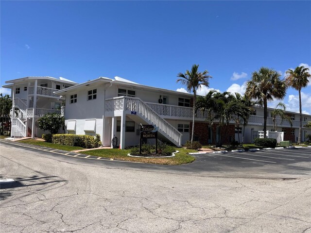 view of building exterior with stairway and uncovered parking