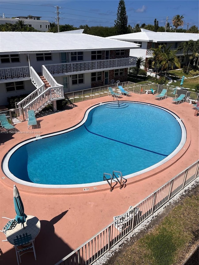 community pool with a patio area and fence