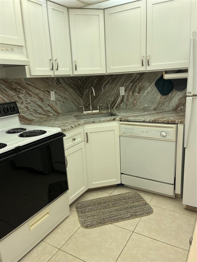 kitchen featuring light tile patterned floors, exhaust hood, white appliances, a sink, and decorative backsplash