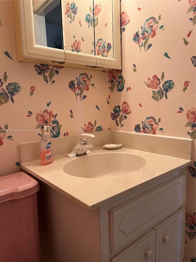 half bath with vanity and wallpapered walls