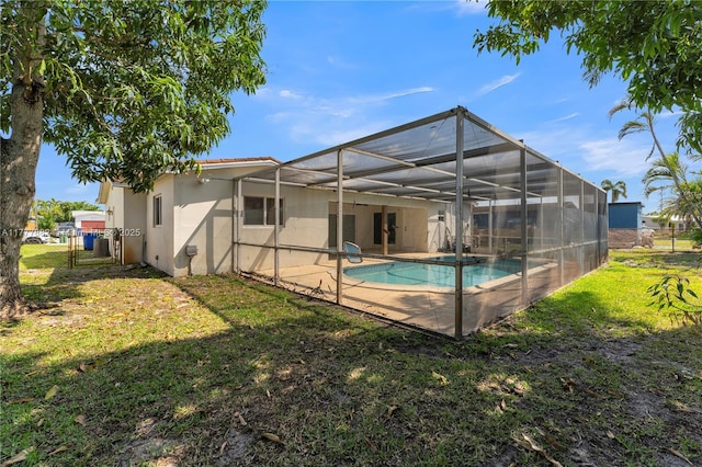 back of property with a patio area, a lawn, fence, stucco siding, and a lanai