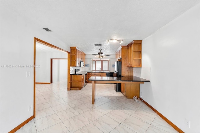 5300 Adams St, Hollywood, FL 33021 - kitchen with open shelves, a textured ceiling, brown cabinetry, freestanding refrigerator, and dark countertops