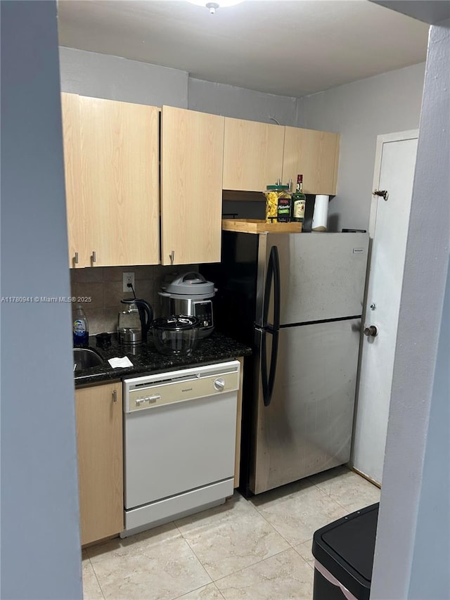 2899 Collins Ave Unit 708, Miami Beach, FL 33140 - kitchen with white dishwasher, light brown cabinets, freestanding refrigerator, dark countertops, and backsplash