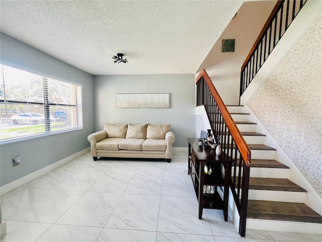 living area featuring stairs, marble finish floor, baseboards, and a textured ceiling
