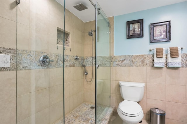 full bathroom featuring toilet, tiled shower, visible vents, and tile walls