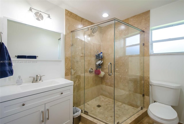 full bath featuring toilet, vanity, and a shower stall