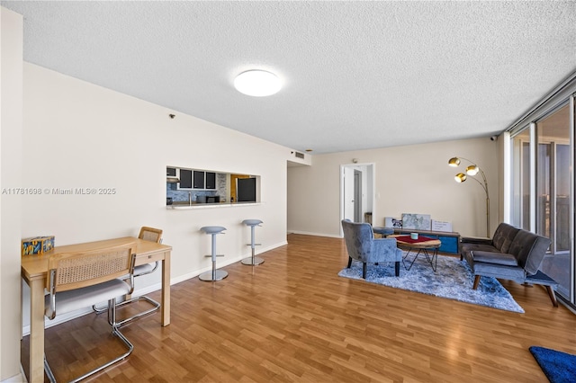 living room featuring visible vents, a textured ceiling, baseboards, and wood finished floors