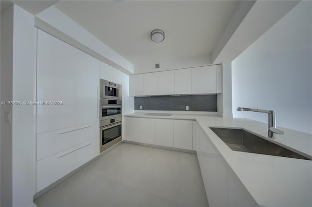 300 Sunny Isles Blvd Unit 4-1904, Sunny Isles Beach, FL 33160 - kitchen with modern cabinets, a sink, decorative backsplash, white cabinetry, and light countertops