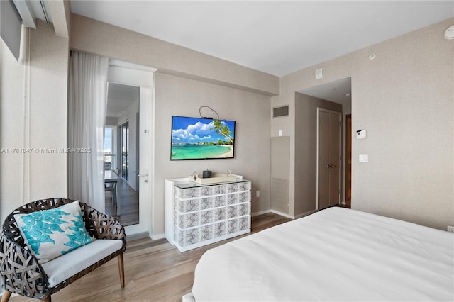 bedroom featuring baseboards, visible vents, and wood finished floors