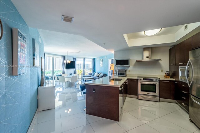 250 Sunny Isles Blvd Unit 3-805, Sunny Isles Beach, FL 33160 - kitchen featuring stainless steel appliances, wall chimney range hood, a peninsula, open floor plan, and light countertops