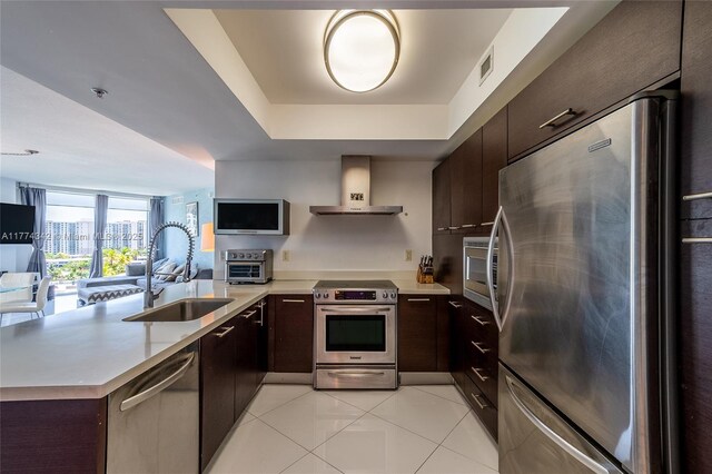 250 Sunny Isles Blvd Unit 3-805, Sunny Isles Beach, FL 33160 - kitchen with stainless steel appliances, wall chimney exhaust hood, a tray ceiling, a peninsula, and light countertops