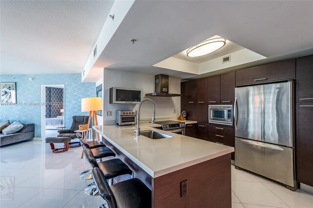 250 Sunny Isles Blvd Unit 3-805, Sunny Isles Beach, FL 33160 - kitchen featuring appliances with stainless steel finishes, wall chimney range hood, light tile patterned floors, and a kitchen breakfast bar
