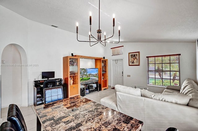 living room featuring light tile patterned floors, an inviting chandelier, vaulted ceiling, and visible vents