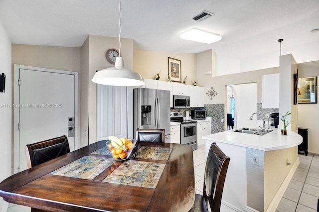 kitchen with decorative backsplash, light tile patterned flooring, white cabinets, a sink, and appliances with stainless steel finishes