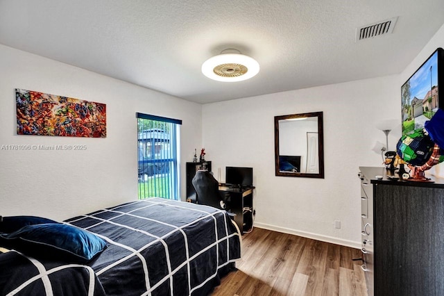 bedroom featuring baseboards, wood finished floors, and visible vents