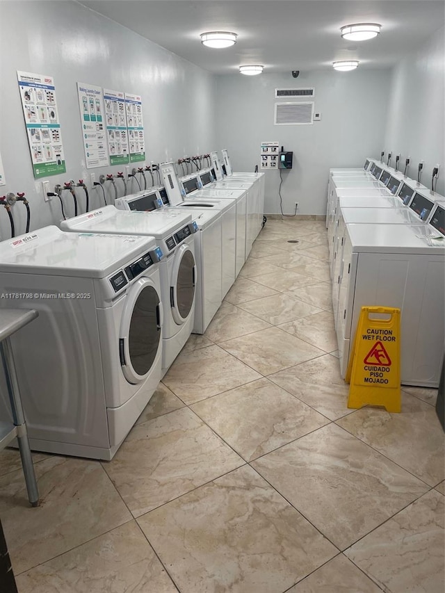 shared laundry area with an AC wall unit, washing machine and clothes dryer, and marble finish floor