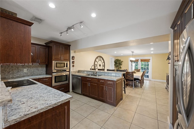 kitchen with visible vents, light tile patterned floors, a sink, a peninsula, and stainless steel appliances