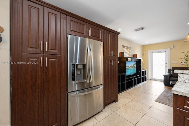 kitchen with dark brown cabinets, visible vents, light stone counters, light tile patterned flooring, and stainless steel fridge