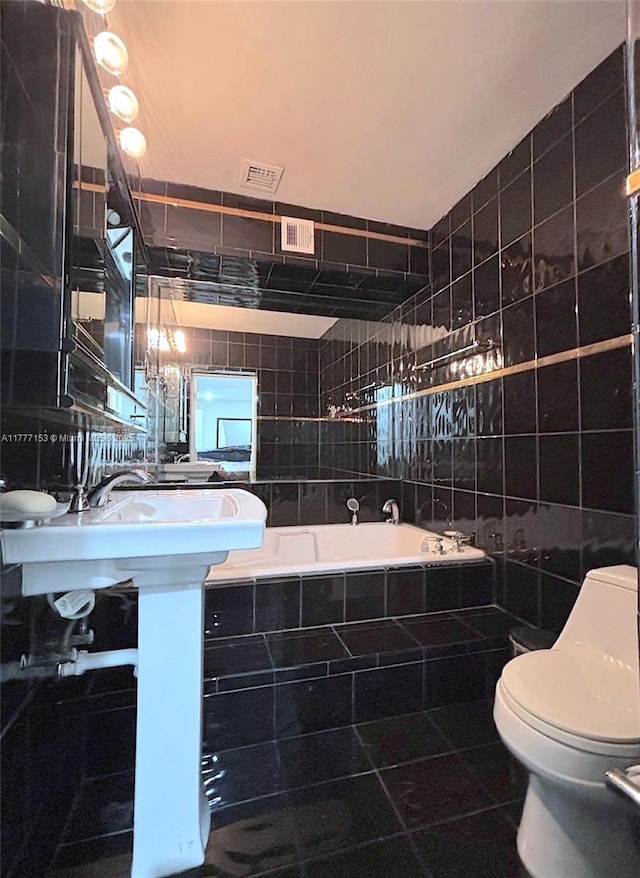 full bath featuring tiled bath, visible vents, tile walls, and toilet
