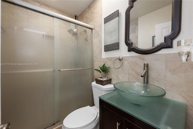 full bathroom with a shower stall, vanity, tile walls, and toilet