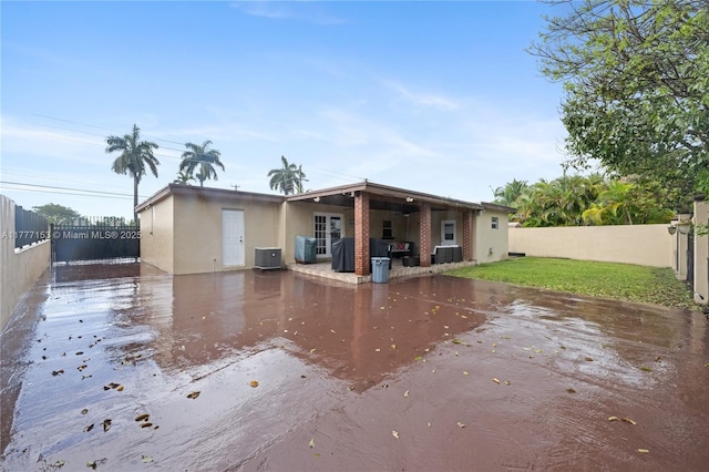 back of house with a patio area, a fenced backyard, and central AC