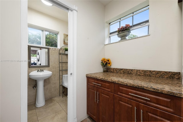 bathroom featuring tile patterned floors, tile walls, and a sink