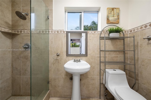 full bathroom with tiled shower, tile walls, a sink, and toilet