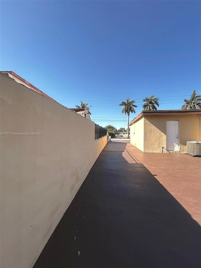 view of side of property with central AC unit, stucco siding, and fence