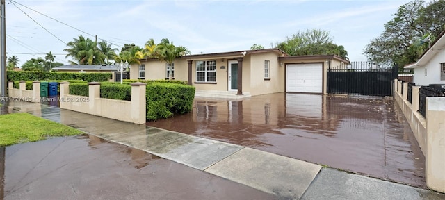 view of front of house with an attached garage, concrete driveway, stucco siding, and fence
