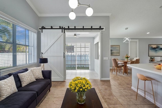 living room with a wealth of natural light, light tile patterned floors, ornamental molding, and a barn door
