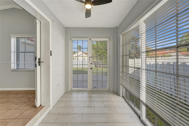 doorway to outside with ceiling fan, light tile patterned flooring, and baseboards