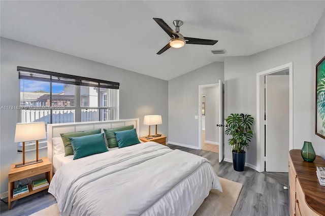 bedroom featuring visible vents, baseboards, a ceiling fan, vaulted ceiling, and wood finished floors