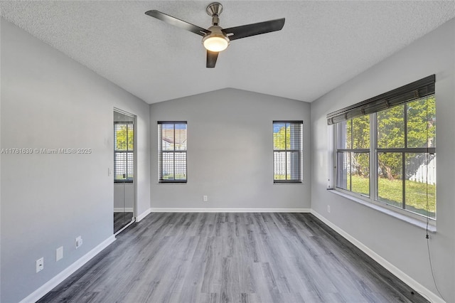 empty room featuring baseboards, ceiling fan, a textured ceiling, wood finished floors, and vaulted ceiling