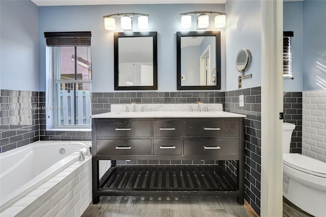 bathroom with a sink, double vanity, toilet, tile walls, and a garden tub